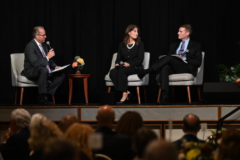 3 individuals speaking on stage