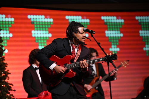 Man playing a guitar on stage during the sounds of the season