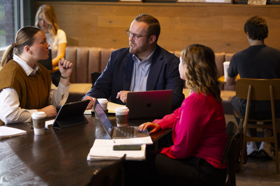 Two women and a man studying in a coffee shop.