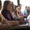 Group of Students in a class room. There is a girl asking a question to the professor.