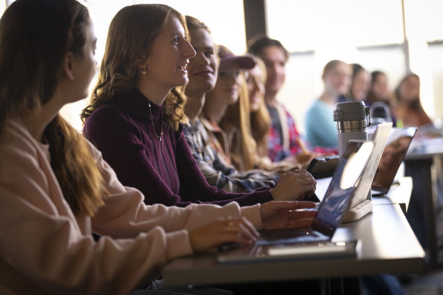 Group of Students in a class room. There is a girl asking a question to the professor.