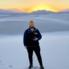 Steven standing in front of snow covered hills during a sun setting