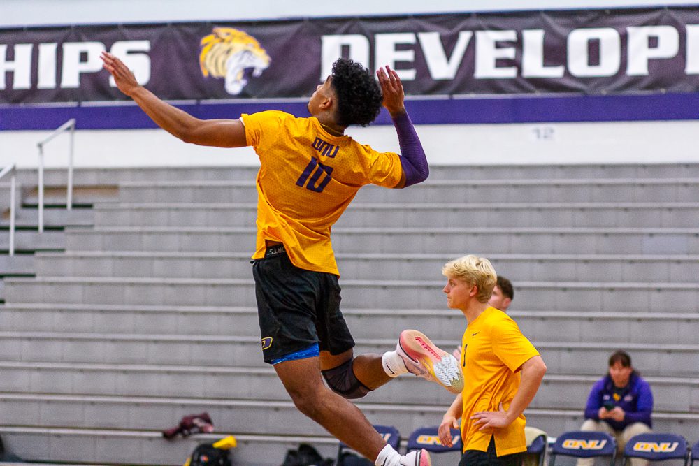 #10 is in the air ready to strike for his volleyball team