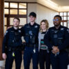Three police officers standing with a professor for a picture.