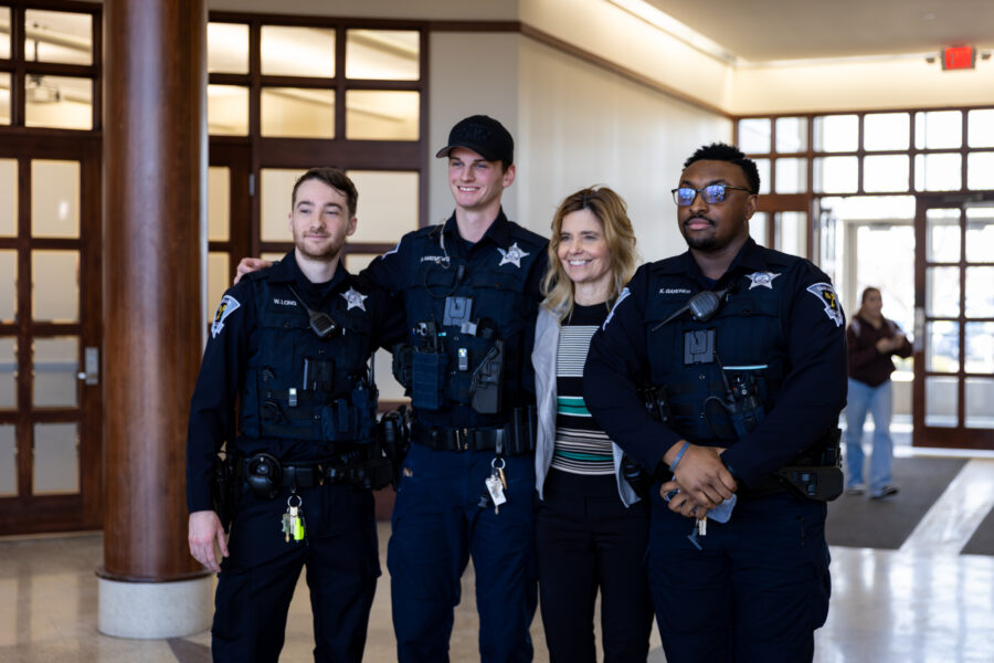 Three police officers standing with a professor for a picture.