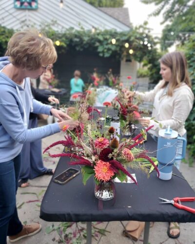 People making flower arrangement on a table.