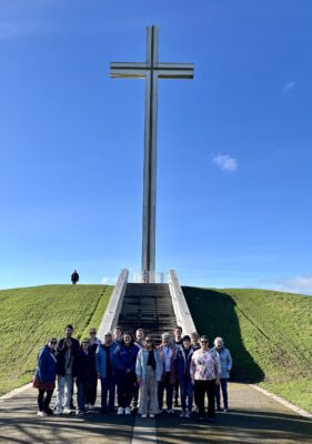 All members of the group standing at the base of a cross.