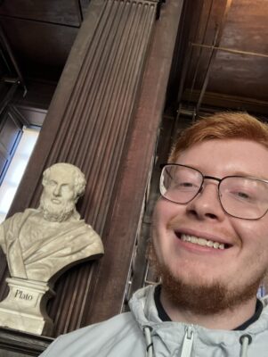 Jacob taking a selfie next to a bust of Plato