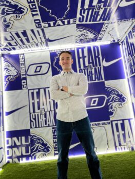 Tyler posing for a photo with an olivet themed background