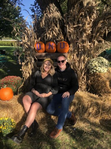 Zach and Ingrid sitting on a hay bale at a pumpkin patch.