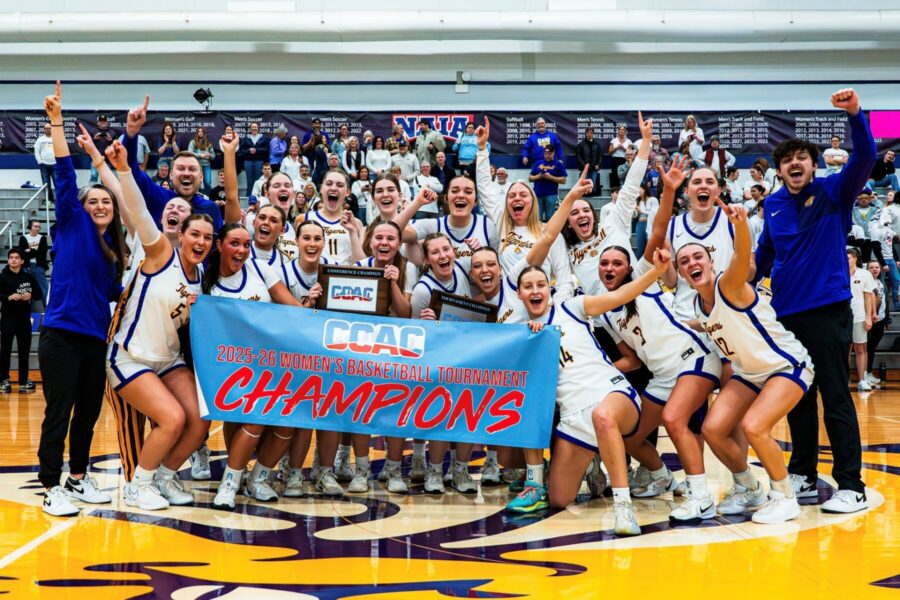 Women's Basketball team holding their championship banner