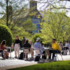 A group of people sitting outside at tables talking.