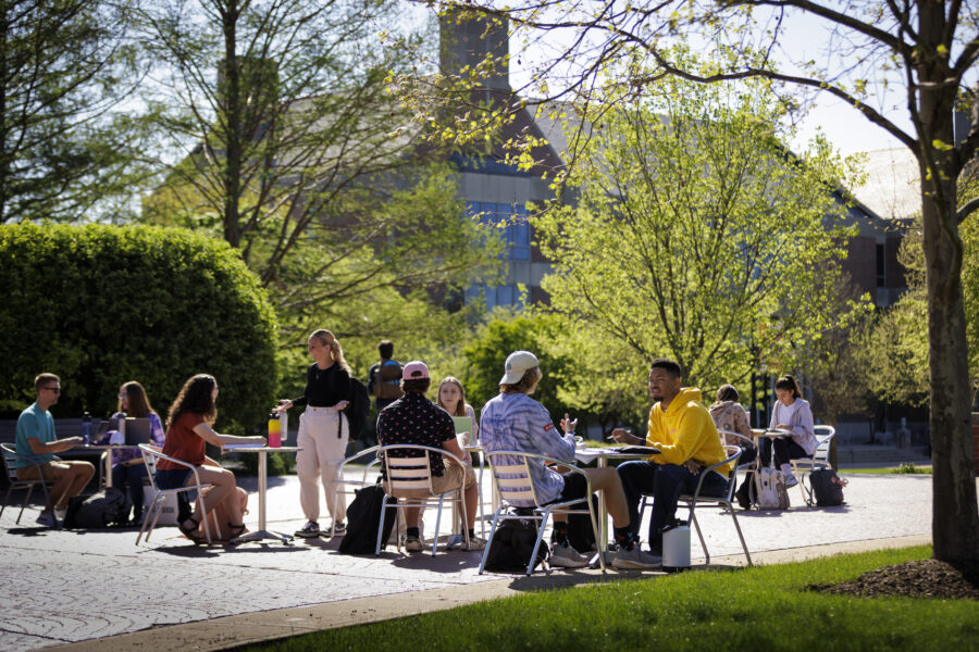 A group of people sitting outside at tables talking.