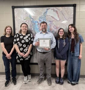 Dr. Carrigan holding his award with some of his student workers for a picture.