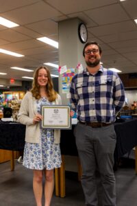 Maddie with a supervisor holding her award for a picture.