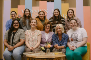 A group of some of the senior women and group leaders sitting and standing behind a couch for a picture.