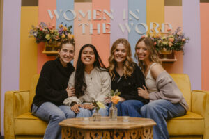 A group of four girls sitting on a couch for a picture.