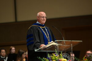Dr. Gregg Chenoweth speaking on stage. 