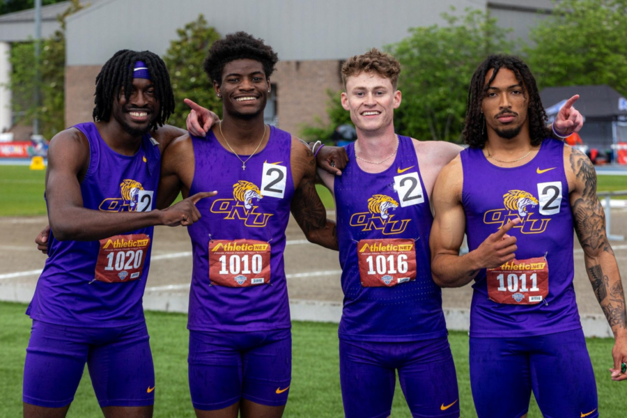 A picture of of Eric White, Connor Price, Noah Mack, and Darrin Dussett in their uniforms at the track.