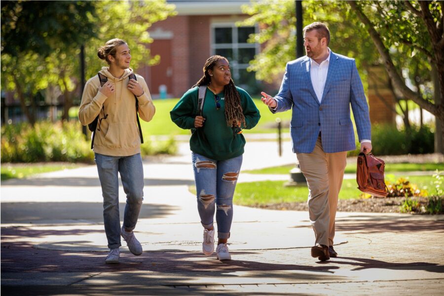 A picture of Jason walking with two students on Olivet's campus.